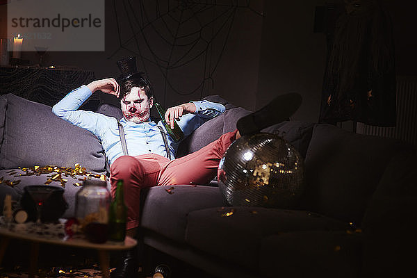 Man in Halloween costume sleeping on couch after party