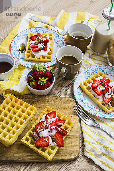 Waffles garnished with strawberries  Greek yogurt and almonds on breakfast table