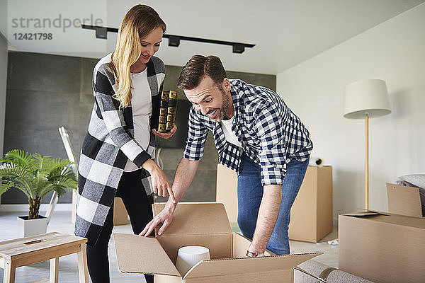 Happy couple moving into new flat unpacking cardboard box
