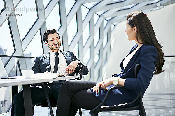 Businesswoman and businessman talking at desk in modern office