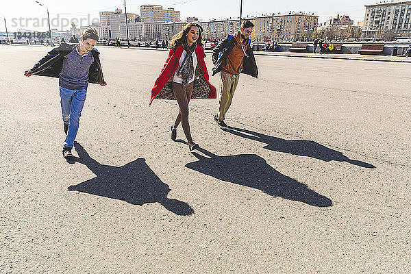 Russia  Moscow  group of friends having fun together and projecting airplane shaped shadows on the ground