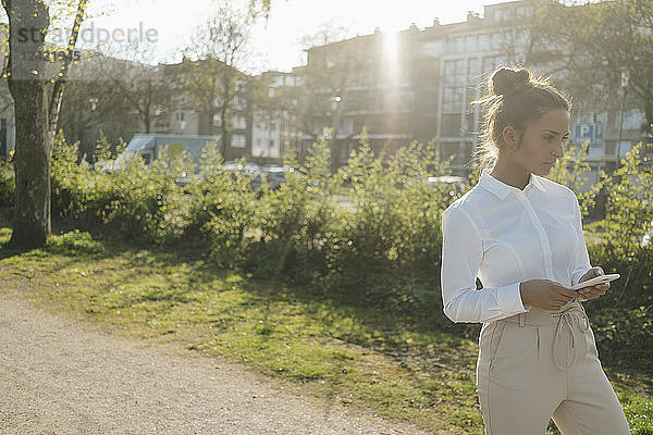 Young businesswoman walking in the city  carrying cup of coffee and a smartphone