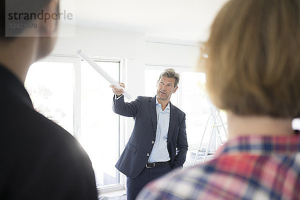 Man in suit talking to couple in unfinished building