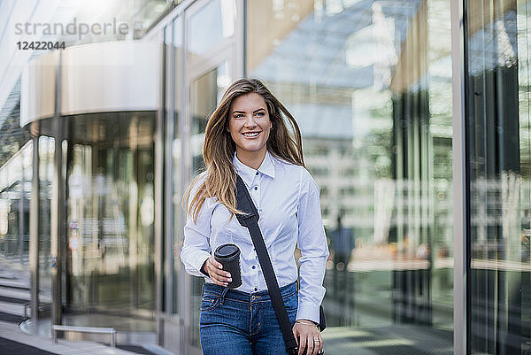 Smiling young businesswoman with bag and coffee to go