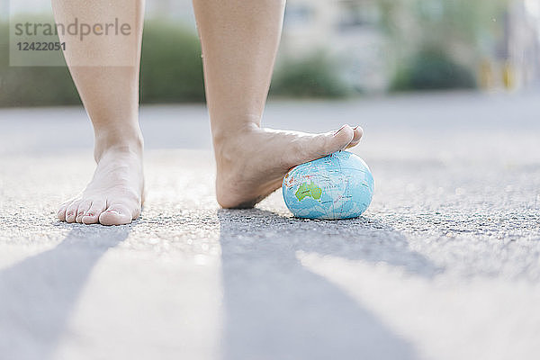 Foot of young woman stepping on globe