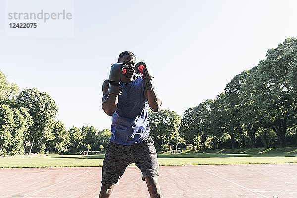 Young Afro-American man training boxing on sports field  outdoors