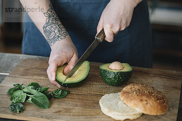 Woman preparing vegan burger  slicing avocado