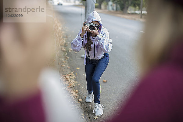 Teenage girl taking a picture of her friends on the street