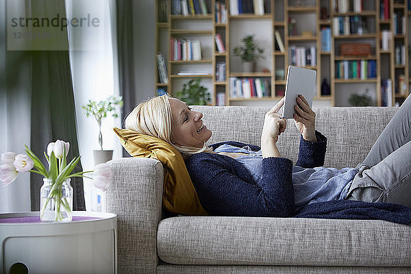 Woman using digital tablet  relaxing on couch