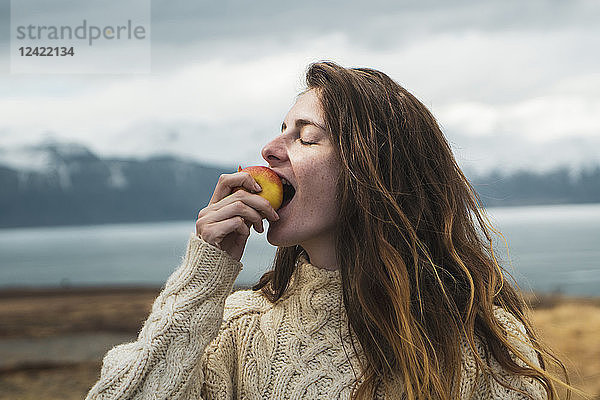 Iceland  woman eating an apple at lakeside