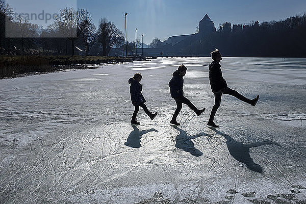 Three children playing on icy surface