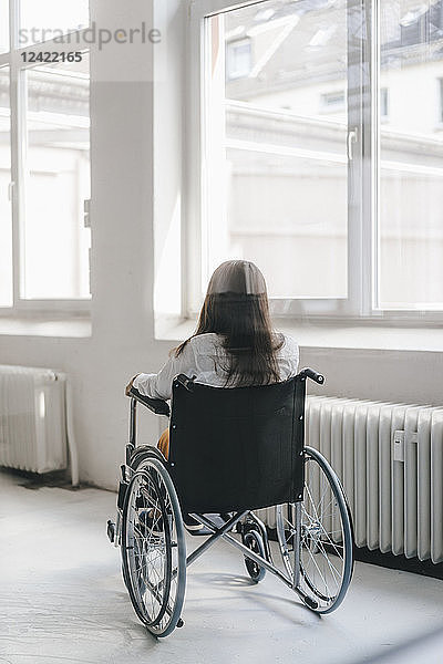 Young handicapped woman sitting in wheelchair  rear view