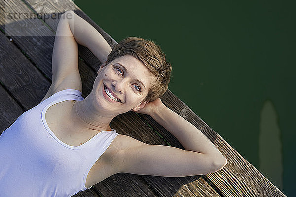 Portrait of smiling woman lying on jetty