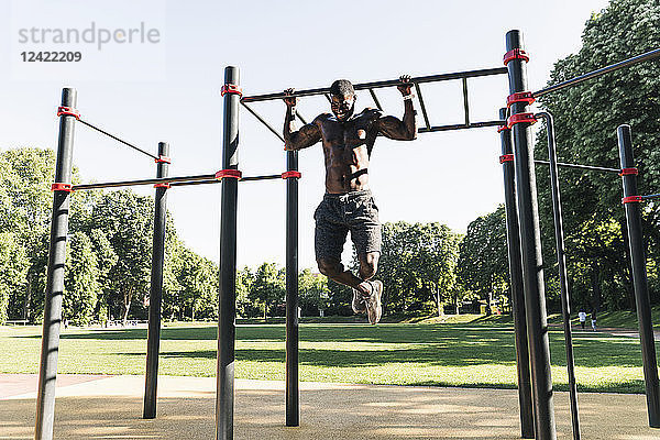 Muscular young man exercising on parcours bars