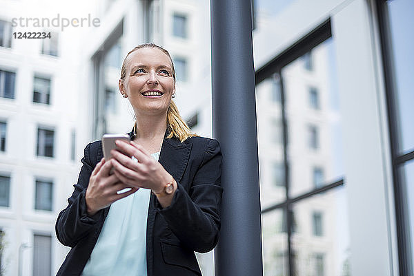 Portrait of smiling businesswoman with cell phone waiting