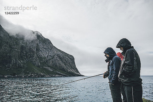 Norway  Lofoten  Moskenesoy  Young men fishing at Horseid Beach