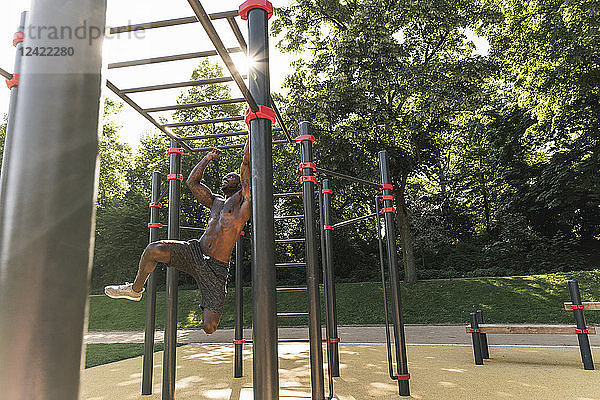 Muscular young man exercising on parcours bars
