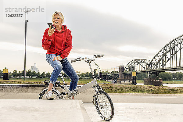 Senior woman with city bike using cell phone