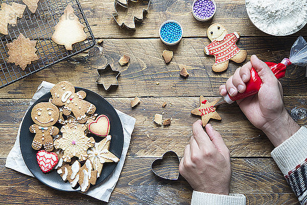 Man's hand decorating Christmas cookie