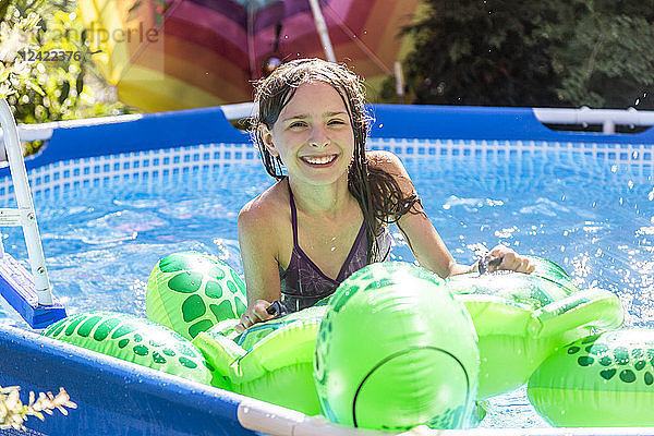 Portrait of smiling girl with swim toy in paddling pool