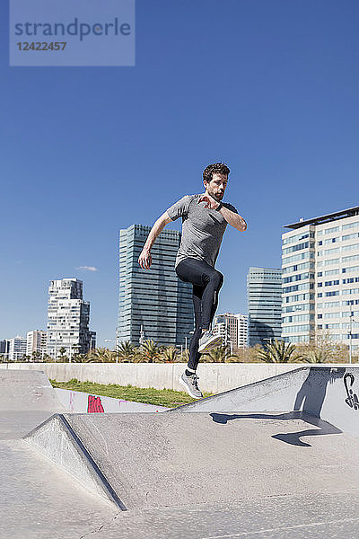 Sportive man jumping in a skatepark in the city