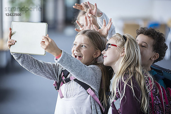 Happy pupils taking a selfie with tablet in school