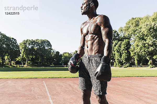 Young Afro-American man training boxing on sports field  outdoors