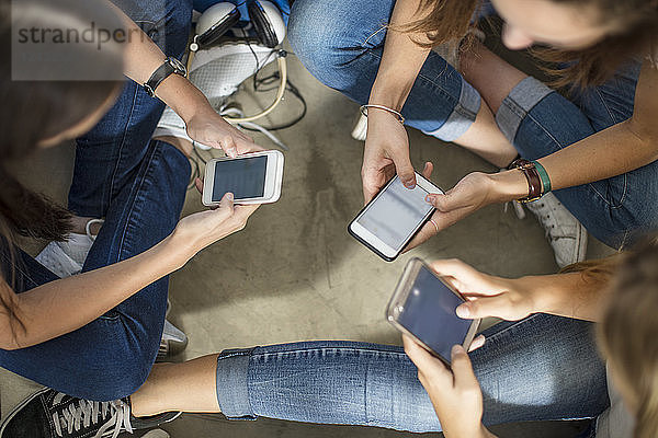 Teenage girls sitting on the floor using cell phones