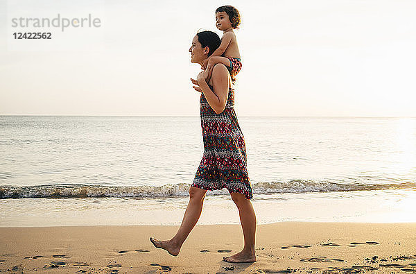 Thailand  Krabi  Koh Lanta  Mother with little daughter on her shoulders on the beach at sunset