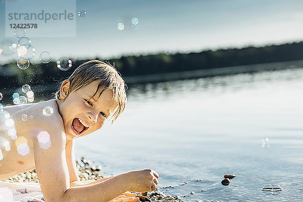 Happy boy at a lake surrounded by soap bubbles