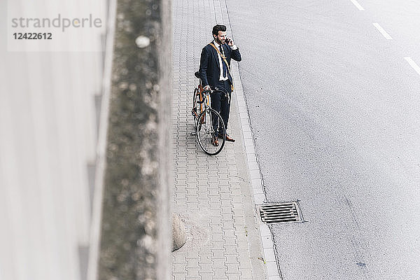 Businessman with bicycle on cell phone at the street