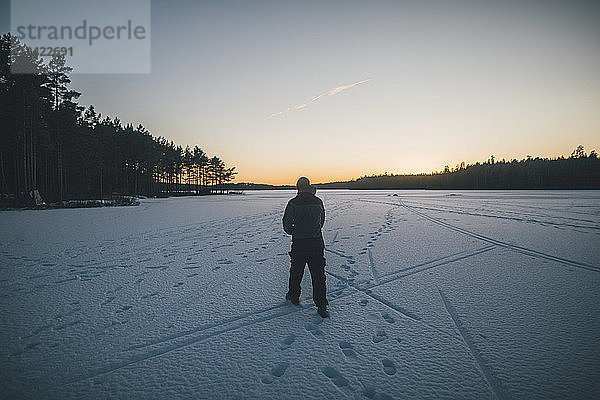 Sweden  Sodermanland  man walking on frozen lake Navsjon in winter