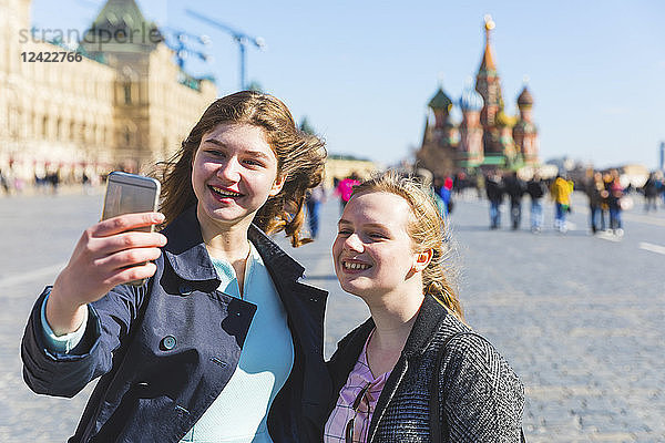 Russia  Moscow  Two teenage girls taking a selfie on the Red Square in the city
