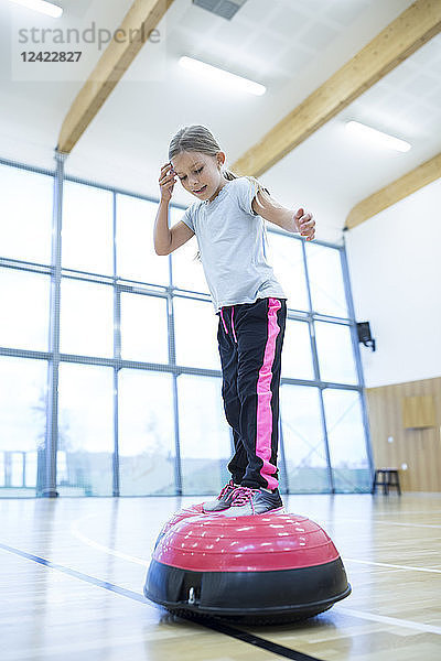 Schoolgirl balancing on exercise equipment in gym class