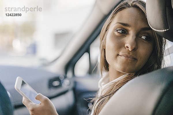 Young businesswoman sitting in car  using smartphone