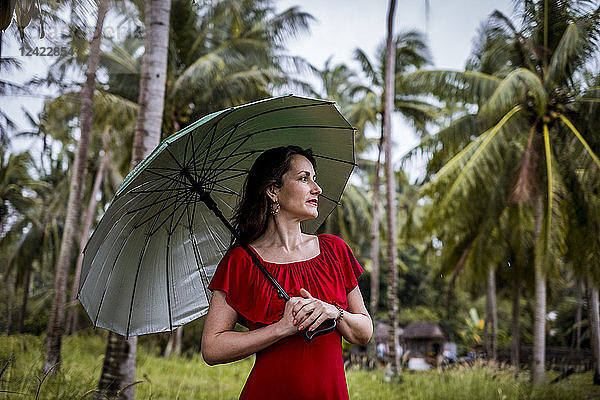 Thailand  Koh Phangan  portrait of woman strolling with umbrella