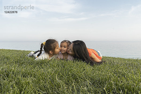 Mother with two daughters kissing at the coast