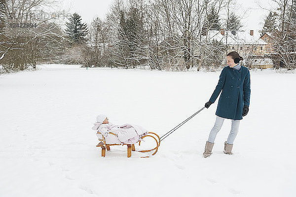 Mother pulling little daughter on sledge