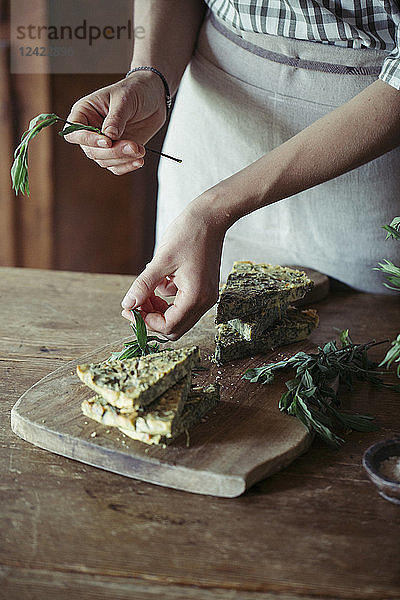 Young woman garnishing homemade chickpea and herb cake