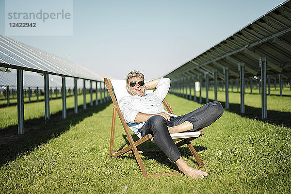 Mature man sitting in beach lounger  solar plant