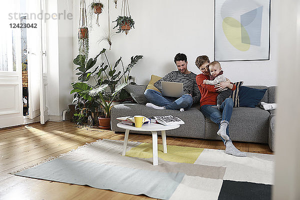 Family sitting on couch  using laptop