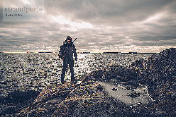 Sweden  Sodermanland  backpacker standing at the seashore under cloudy sky