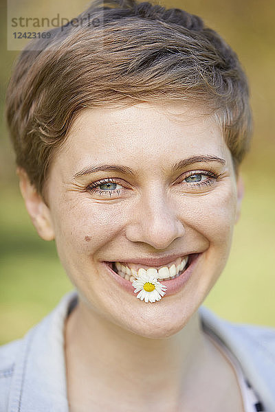 Portrait of laughing woman with daisy in mouth