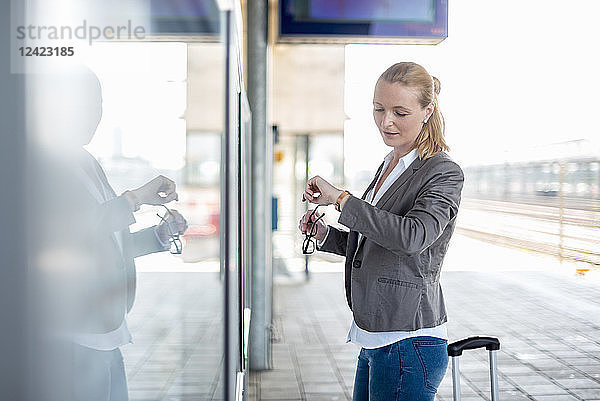 Mature businesswoman standing at platform checking the ime