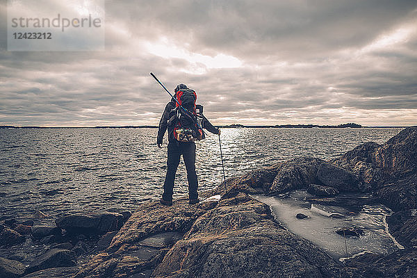 Sweden  Sodermanland  backpacker standing at the seashore under cloudy sky