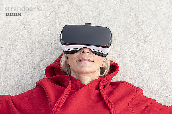 Senior woman lying on the ground wearing VR glasses