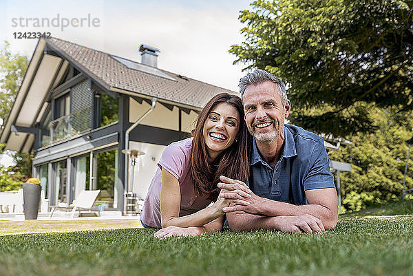 Portrait of happy couple lying in garden of their home