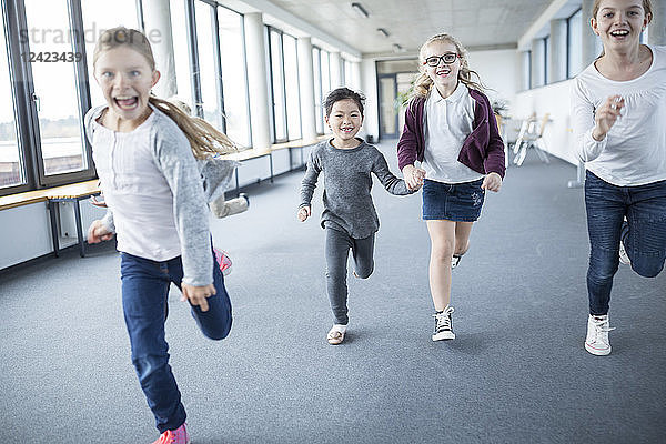 Excited schoolgirls rushing down school corridor