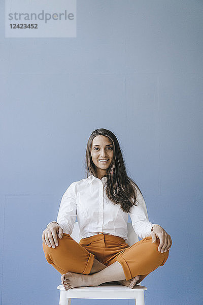 Pretty young woman sitting cross legged on a chair