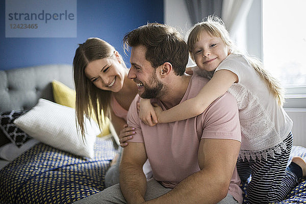 Happy family lsitting on bed  embracing